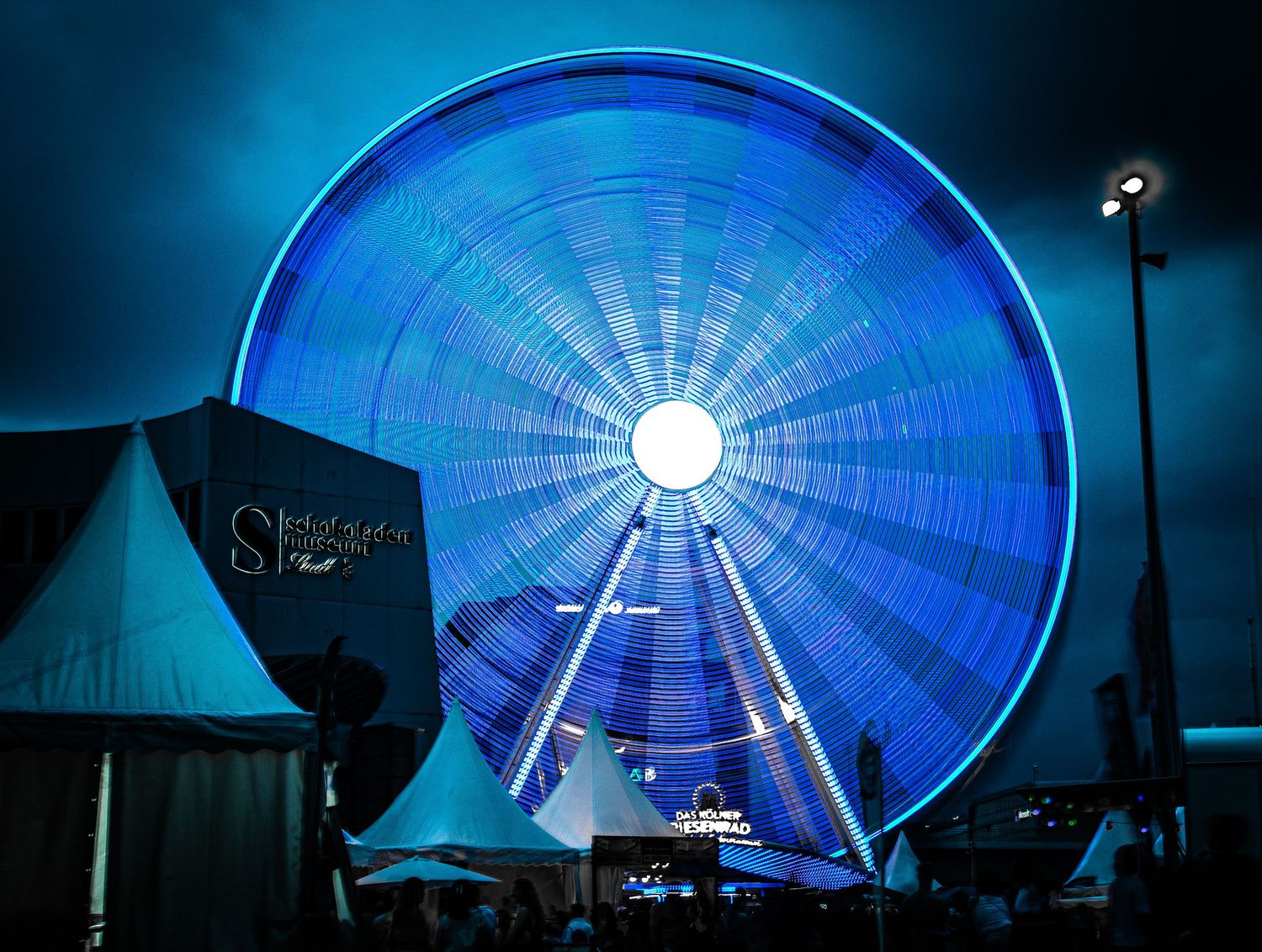 A ferris wheel at night, blurred into blue light by a long exposure
