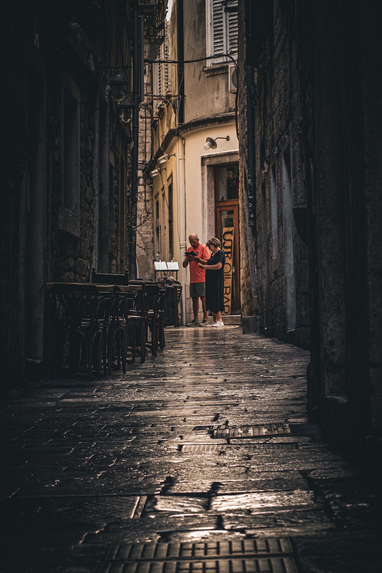 A couple in a narrow old-town lane after rain