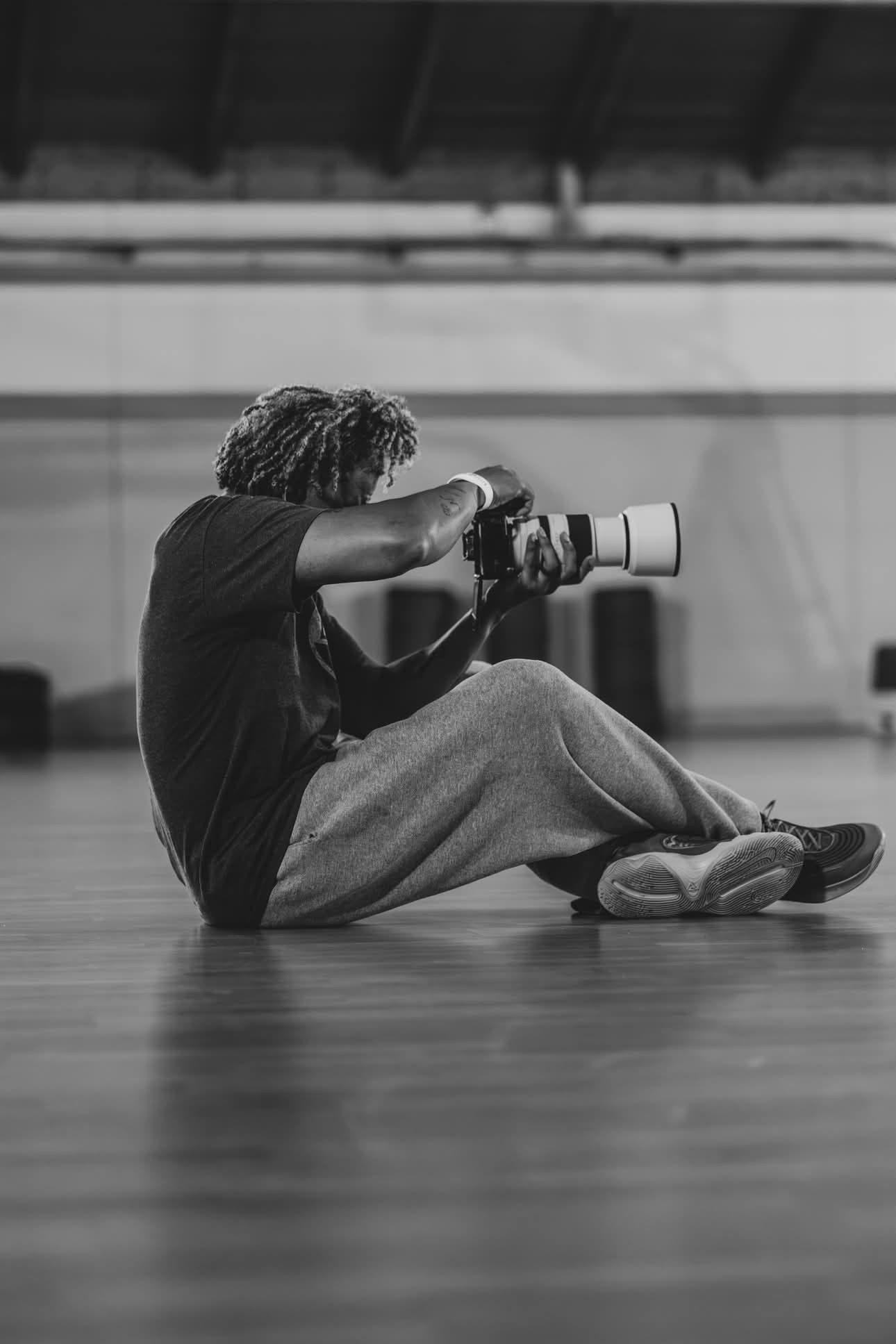 Ritchie Brown sitting on a gym floor, photographing with a long lens
